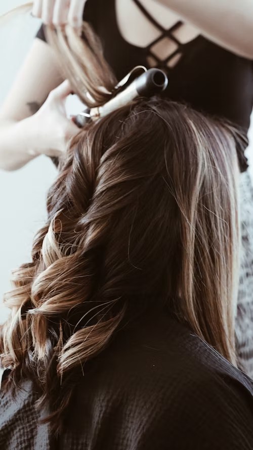 A hairstylist styling the hair of a female for her professional headshot session