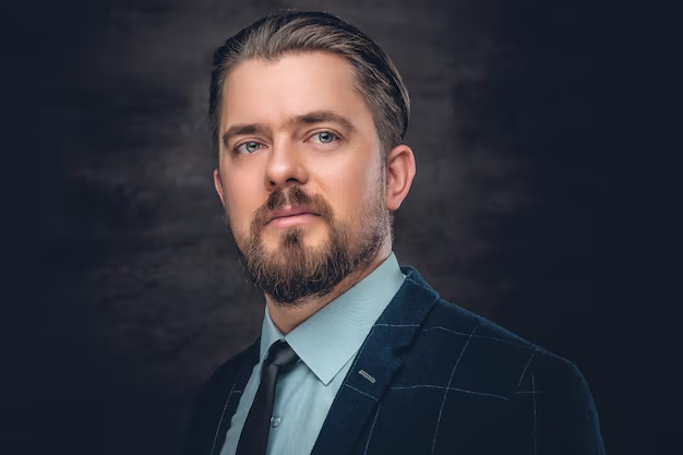 A modern professional headshot of a man against a solid background