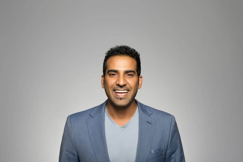 A man in a grey suit giving a big smile for a professional headshot